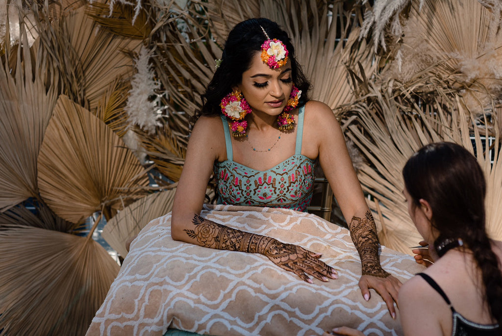 Mehndi Night, a bride getting her Bridal Henna done, wearing Prune India Bespoke Floral, from Bespoke Collection, handcrafted by Leesha Arora  