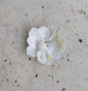 A single white silk flower jhumkas with a mix metal base on a textured background.