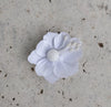 A handcrafted silk flower jhumkas in a mix metal base, primarily white in color, displayed against a textured background.