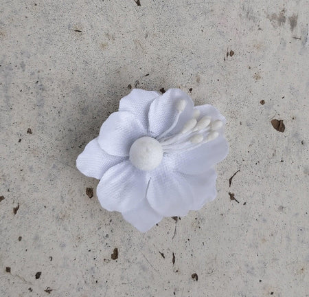 A handcrafted silk flower jhumkas in a mix metal base, primarily white in color, displayed against a textured background.