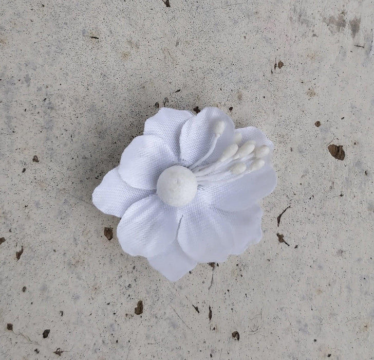 A handcrafted silk flower jhumkas in a mix metal base, primarily white in color, displayed against a textured background.