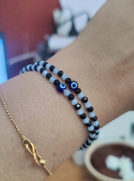 Close-up of a wrist wearing two bracelets evil eye