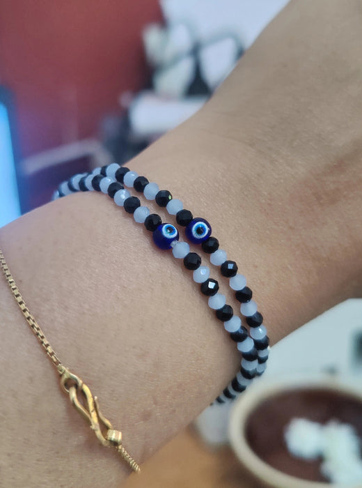 Close-up of a wrist wearing two bracelets evil eye
