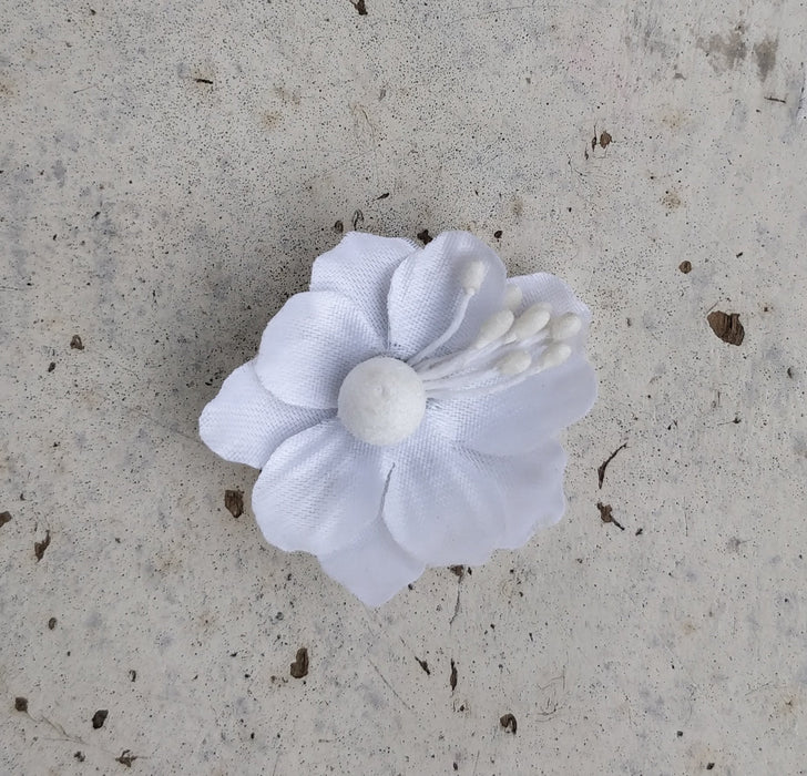 A close-up image of a bridal bangle with attached floral kaleere, featuring a intricate design with silk flowers and beads, held by a hand with nail art.