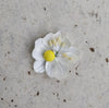 A close-up image of a bridal bangle with attached floral kaleere, featuring a intricate design with silk flowers and beads, held by a hand with nail art.