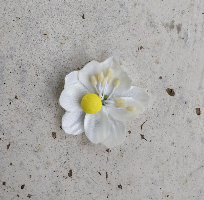 A close-up image of a bridal bangle with attached floral kaleere, featuring a intricate design with silk flowers and beads, held by a hand with nail art.