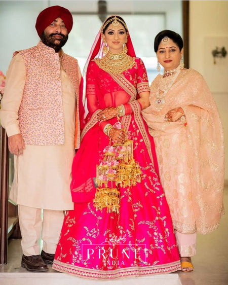 Woman in traditional pink Sabyasachi Bridal Lehnga with jewelry and floral Kaleere by Prune India