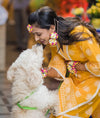 Close-up of handcrafted sustainable floral jhumkie earrings on a real bride  showering love to her dog